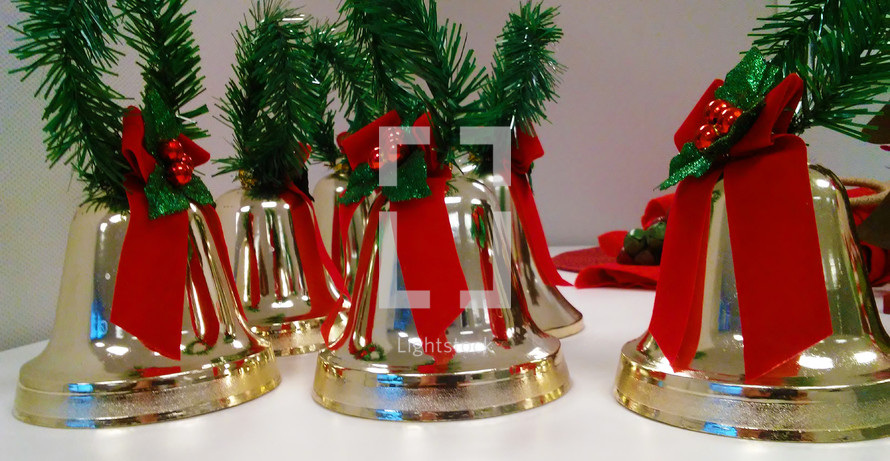 Five Christmas Bells surrounded with red and green Christmas decorations. 