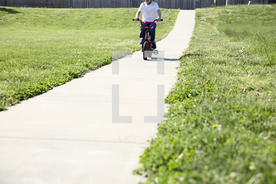 a little boy riding a bicycle on a sidewalk 