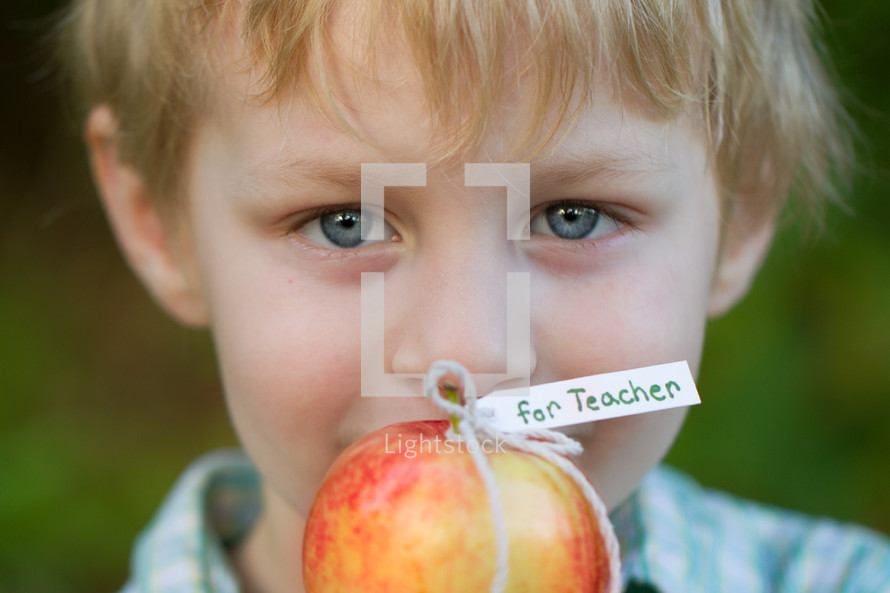 child holding an apple for the teacher 