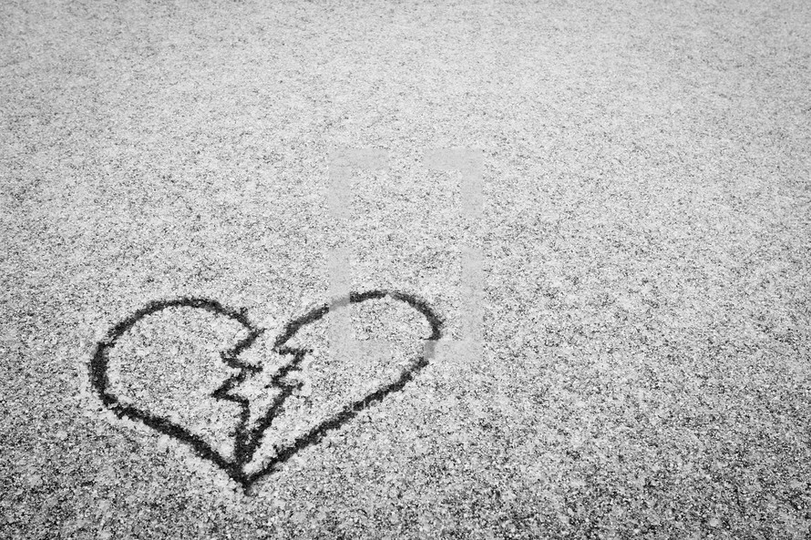 broken heart drawn in the snow on pavement 