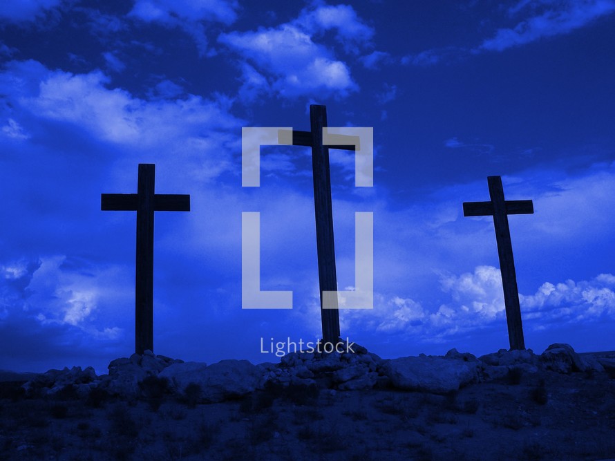 Three crosses of Calvary standing ominously against a dark blue sky 