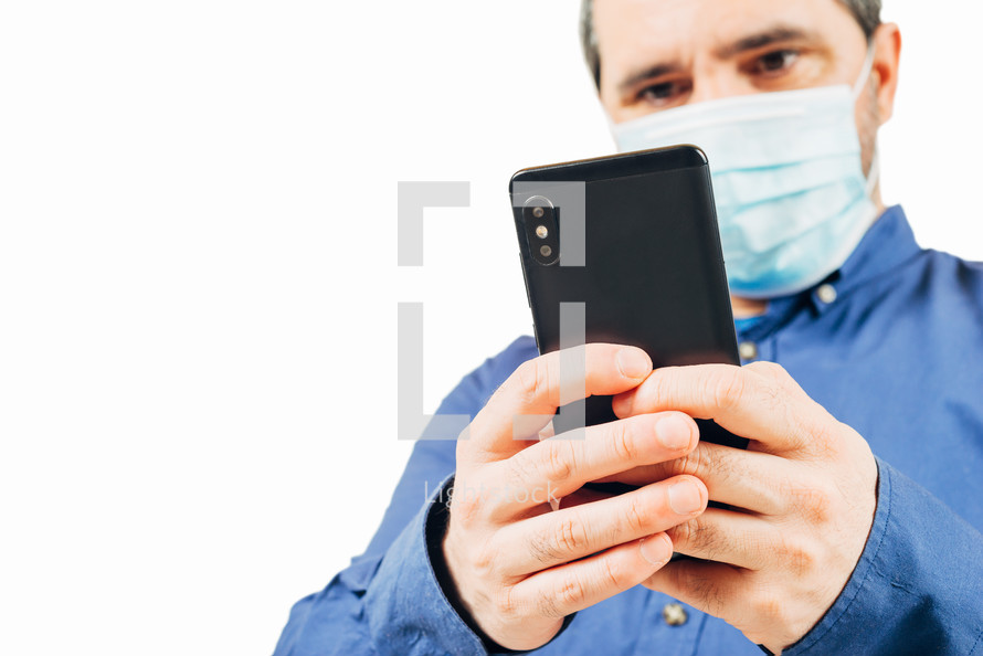 man in medical mask looking at smartphone on white background