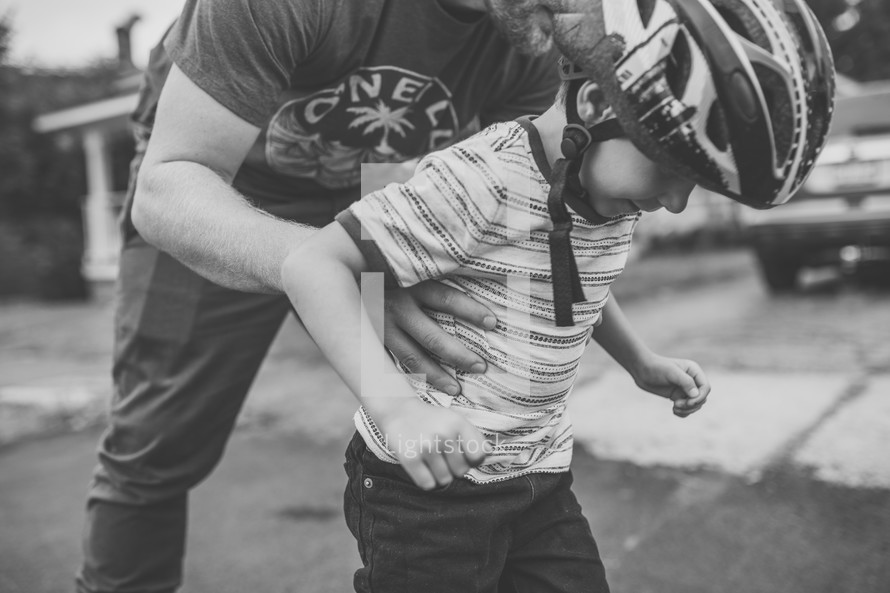 dad helping his son rollerblade 