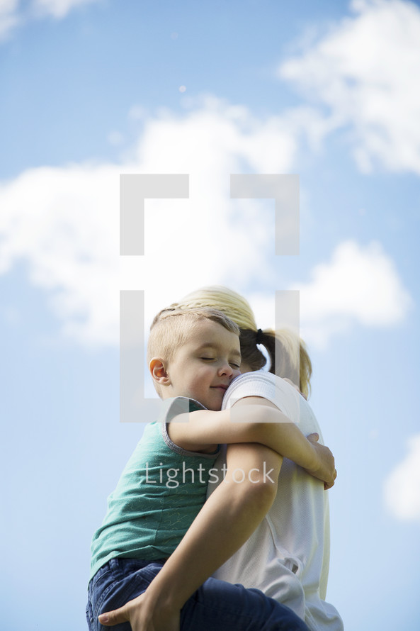 a mother and son hugging outdoors 