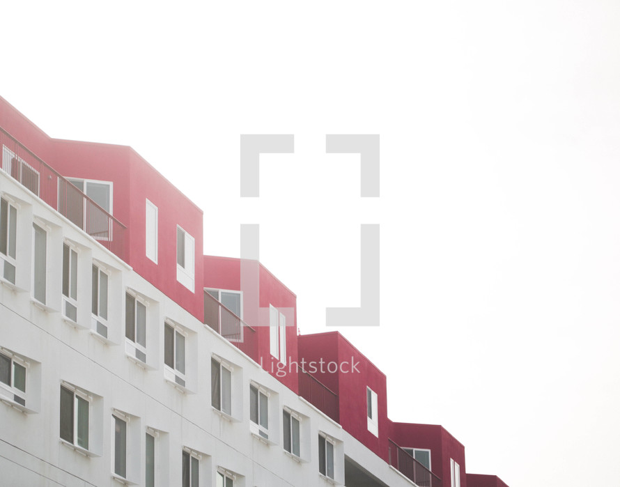 row of windows on a red and white building in fog 