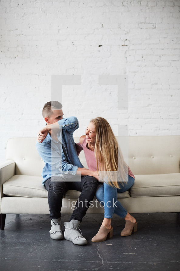 a playing couple sitting on a couch 