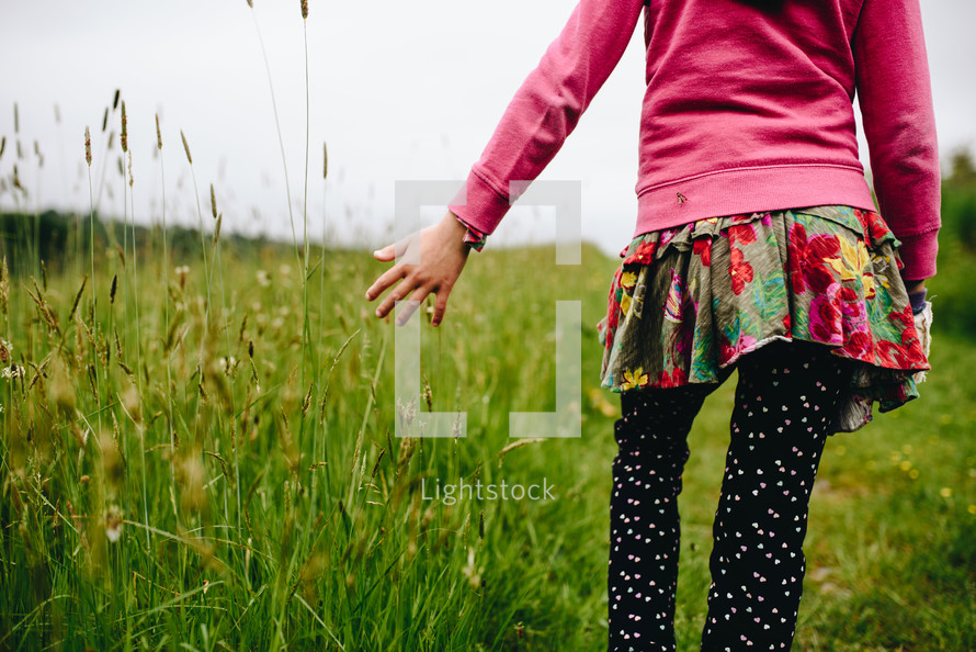 girl walking through tall green grasses 