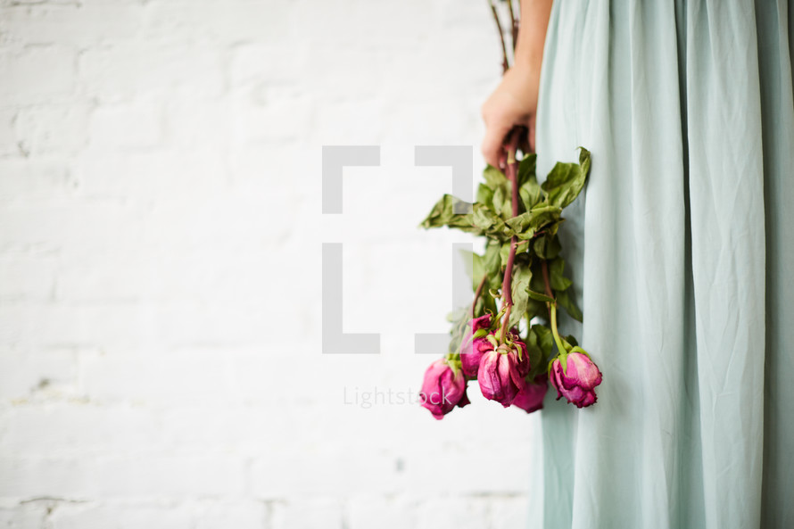 a woman holding a bouquet of dying roses