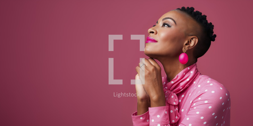 Thoughtful African American woman in a pink polka dot blouse with matching accessories, gazing upwards.