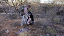 A man picking up trash left in the desert by illegal immigrants