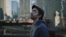 A young man in the middle of the city looking up at tall buildings