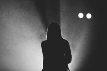 silhouette of a woman standing in a spotlight 