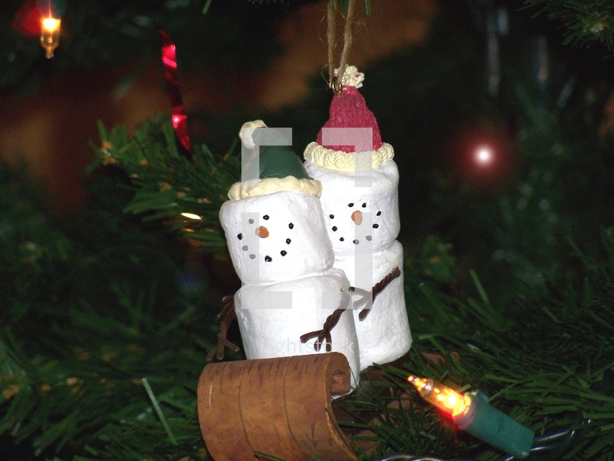 Christmas Marshmallow Sledding team - a male and female Marshmallow couple enjoy sleigh riding on a wooden sleigh in this decorative and whimsical Christmas tree ornament to help celebrate the Christmas holidays giving a fun and festive atmosphere.