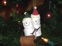 Christmas Marshmallow Sledding team - a male and female Marshmallow couple enjoy sleigh riding on a wooden sleigh in this decorative and whimsical Christmas tree ornament to help celebrate the Christmas holidays giving a fun and festive atmosphere.