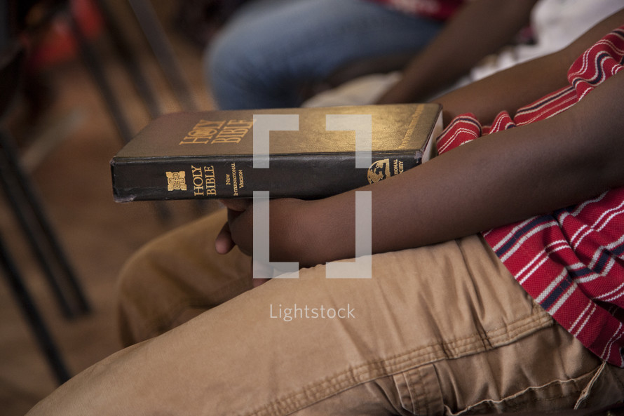 boy child holding a Bible in his lap