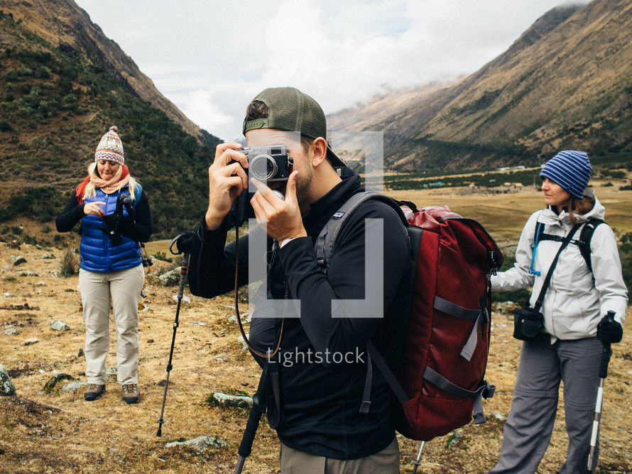 A hiker takes a photograph in the mountains.