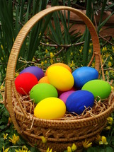 brightly colored Easter eggs in a basket outdoors 