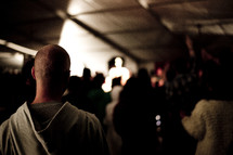 Audience facing an illuminated speaker on stage.