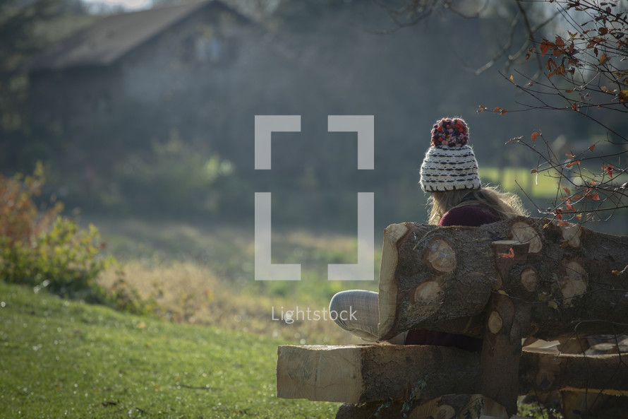 teen girl sitting outdoors in a wool cap