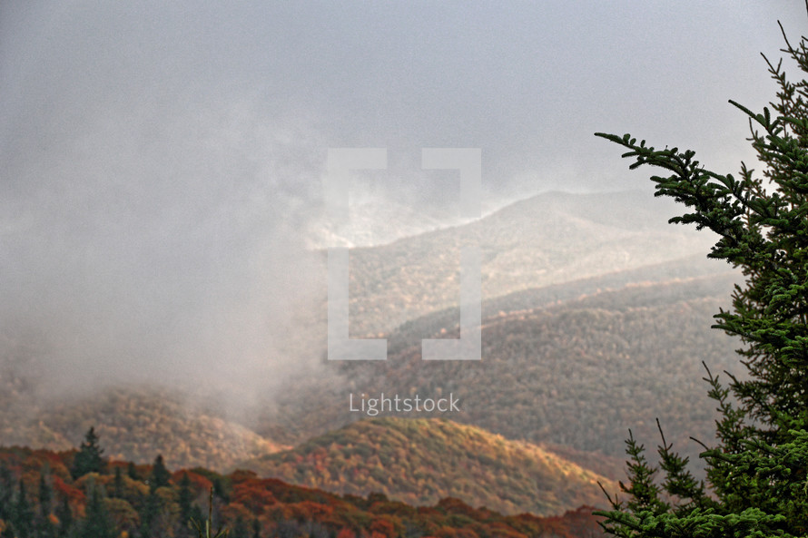 fog and clouds moving over a mountain scene 