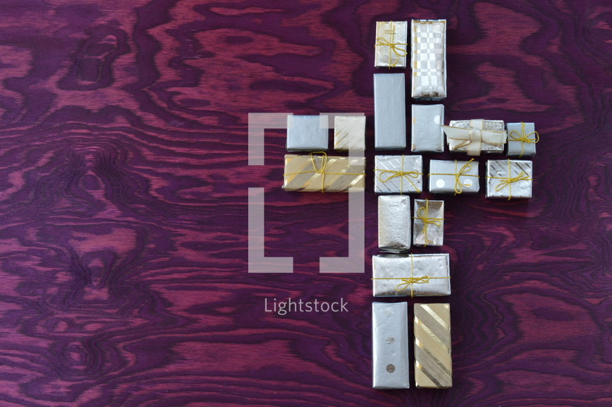 many little presents shaping a cross on purple wooden background