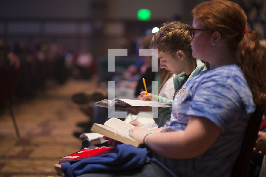 Teens taking notes at a conference.