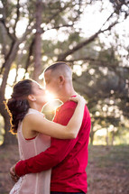 Couple embracing at sunrise in the woods.