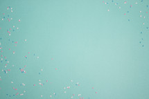 Turquoise background with blue, pink, and white confetti