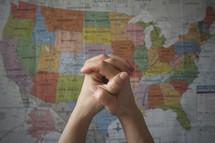 praying hands in front of a map of the United States 