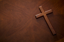 A mahogany wood cross on a similarly textured table top