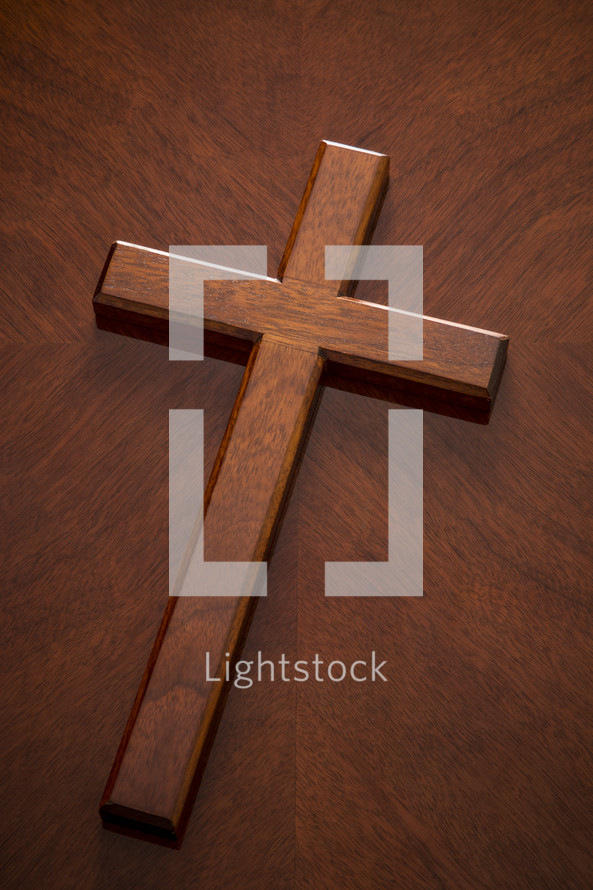 A mahogany wood cross on a similarly textured table top