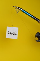 temptation – a piece of paper with the word LUCK written on at the fishhook of an angling rod