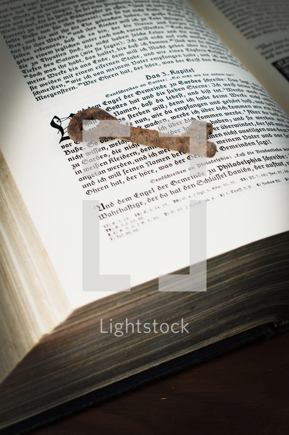 rusty key on the pages of an old book - the key of David on the book of revelations