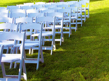 rows of white folding chairs in a lawn for a wedding, graduation commencement or outdoor gathering such as a wedding day in spring or summertime. 