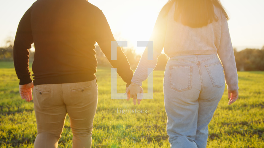 Lovely couple walk in the countryside to the sunset hand by hand