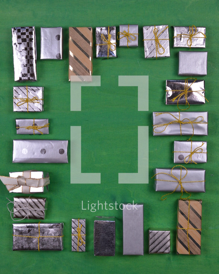 many little silver and golden presents building a frame on green wooden background