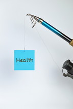 the word health on a cyan piece of paper hanging from a fishing line 
