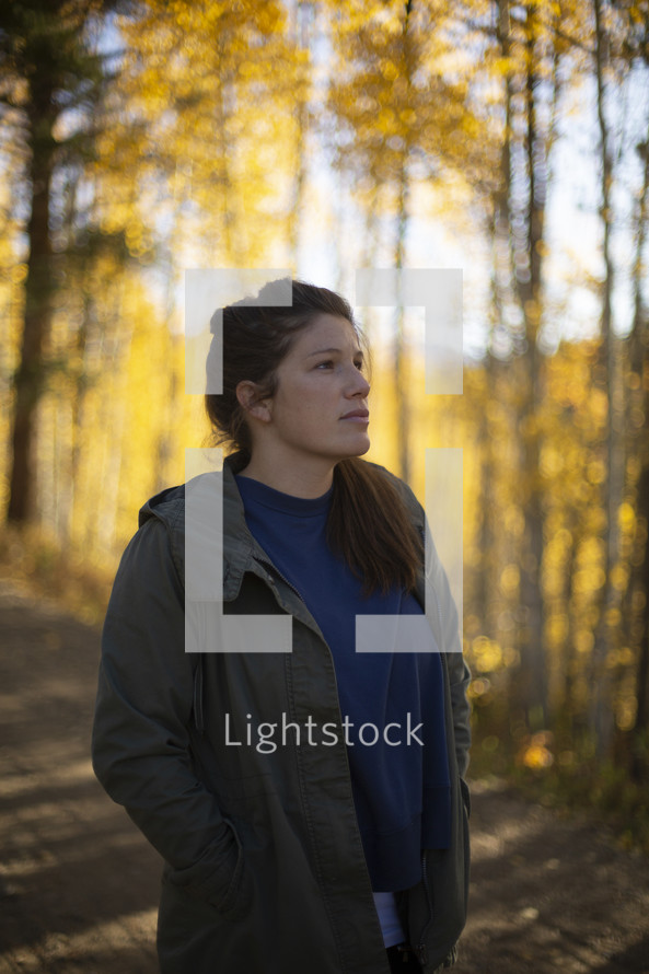 young woman looking up at fall leaves 