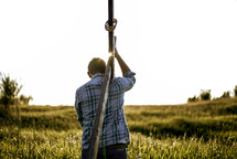 man carrying a cross through a field 