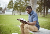 a man reading a Bible outdoors
