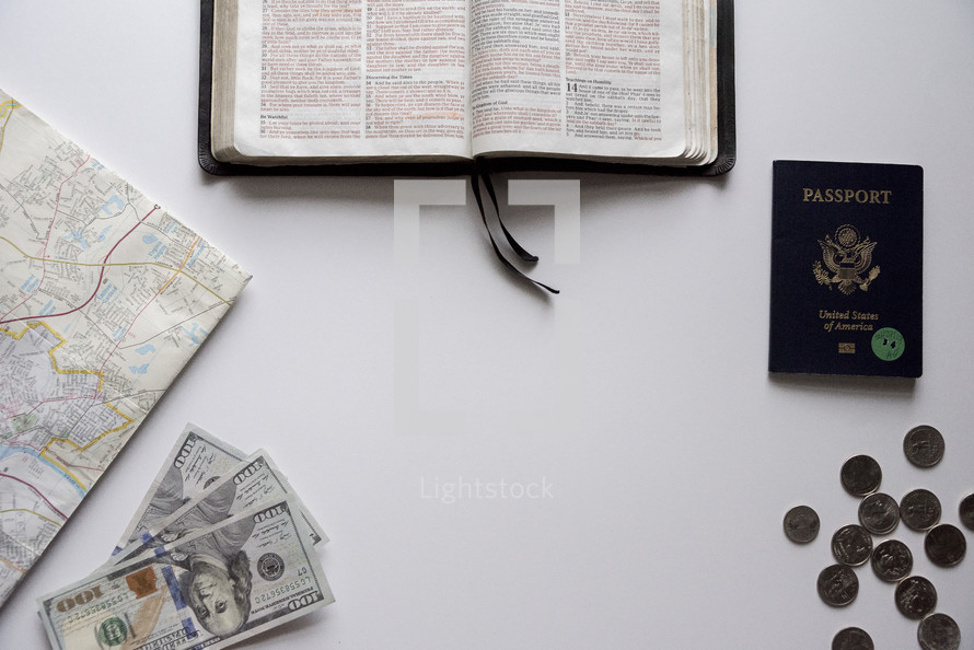 map, passport, Bible, coins, and cash on a white background 