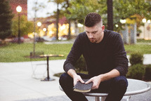 a man holding a Bible praying outdoors 