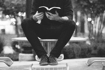  a man reading a Bible outdoors 