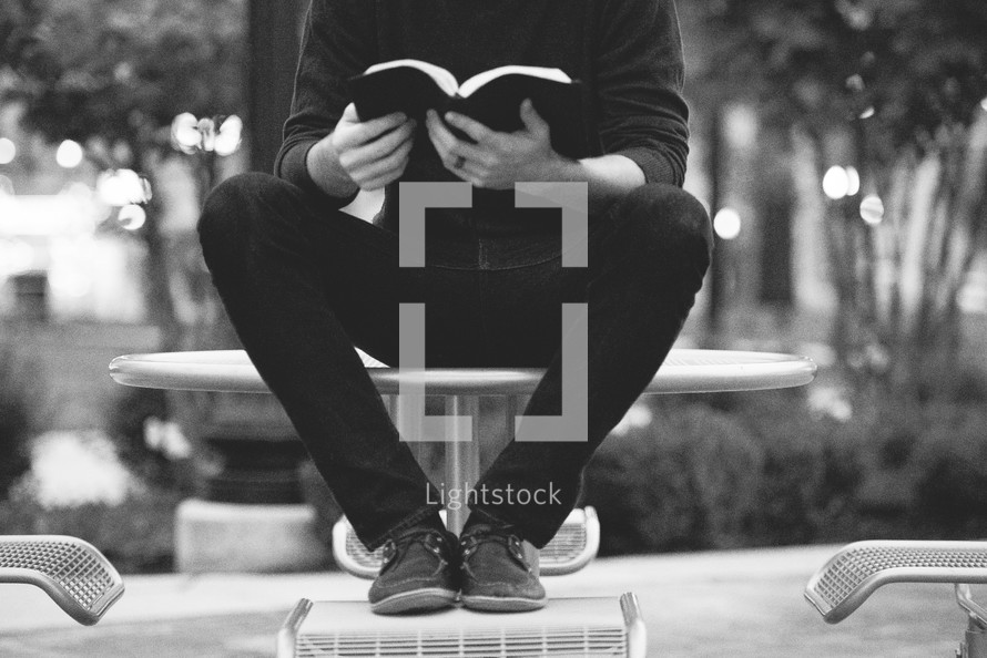  a man reading a Bible outdoors 