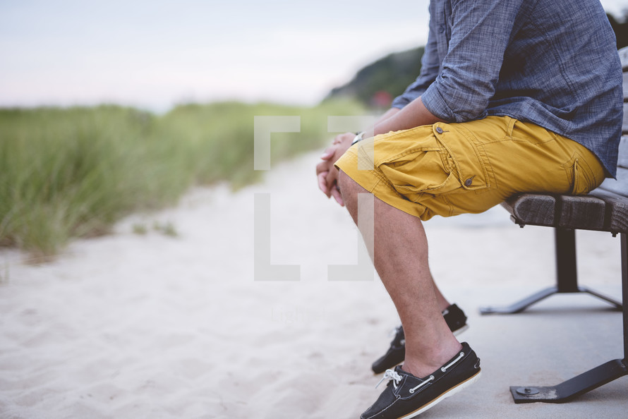 man sitting on a bench on a beach 
