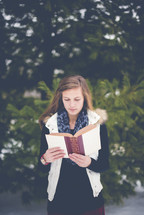 girl reading a Bible outdoors in winter 