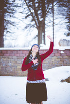 a woman standing in the snow praising God 