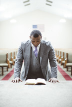 a man praying over a Bible in a church 