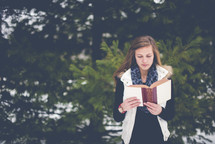 girl reading a Bible outdoors 
