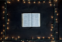 Pages of an opened Bible with Christmas lights border 